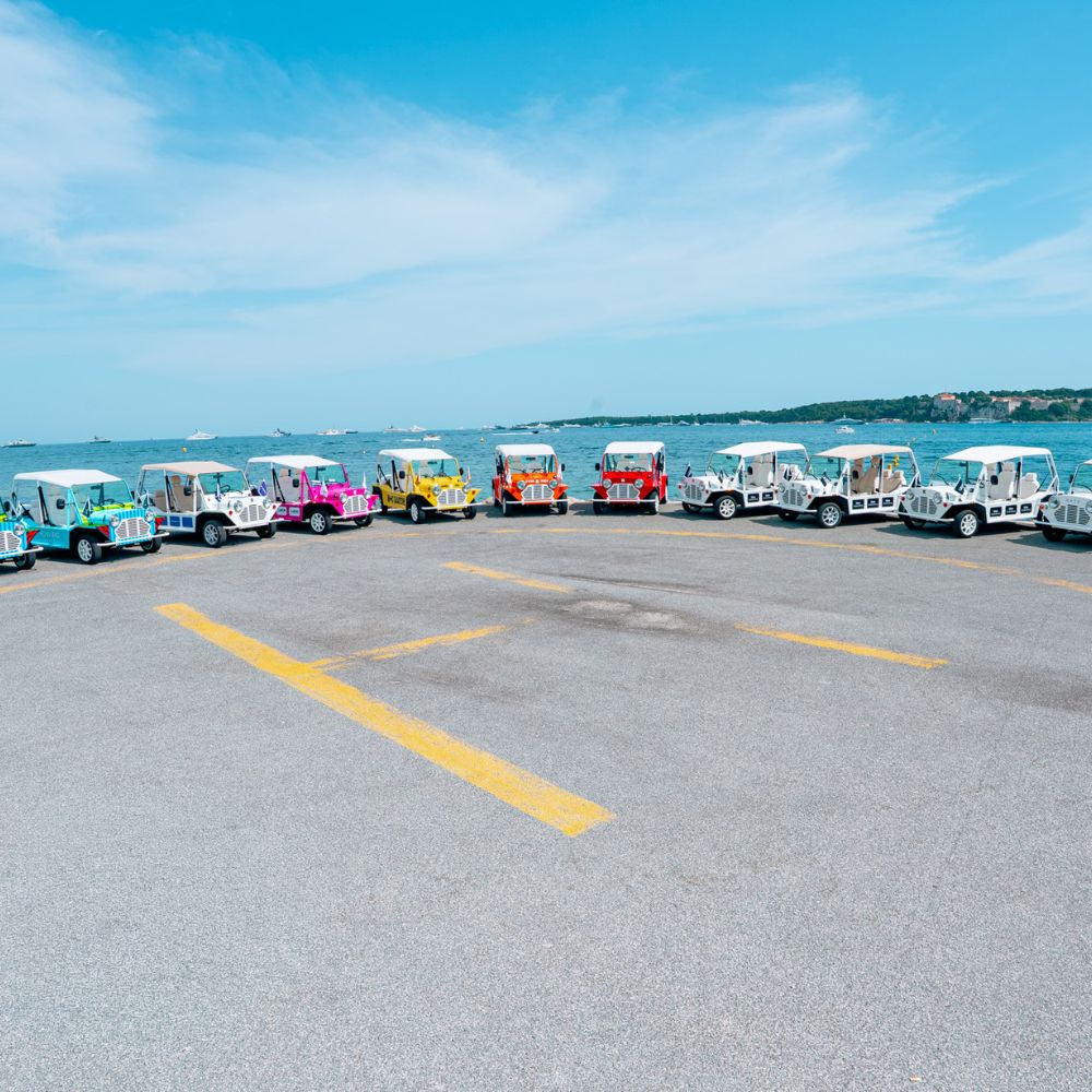 Flotte de Mini Moke électriques multicolores face à la baie de Cannes